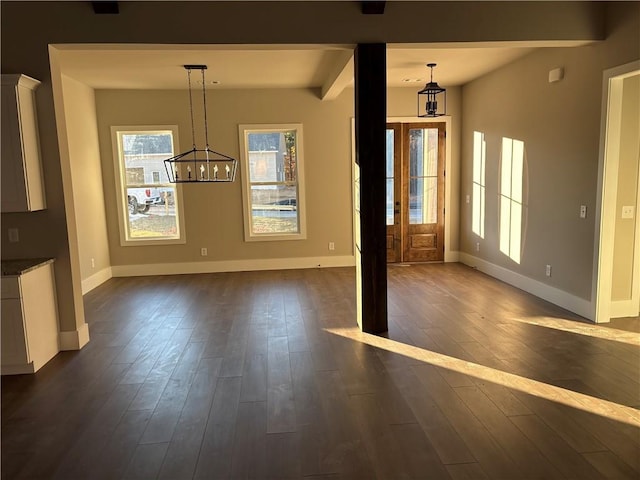 unfurnished dining area featuring beamed ceiling, dark wood-type flooring, and a notable chandelier