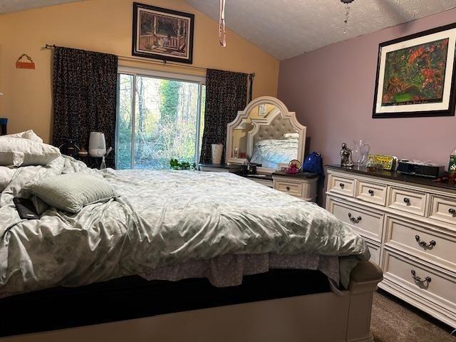 bedroom featuring a textured ceiling, vaulted ceiling, and dark colored carpet