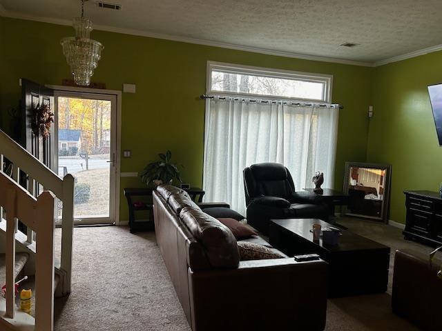 carpeted living room featuring a notable chandelier, ornamental molding, and a textured ceiling