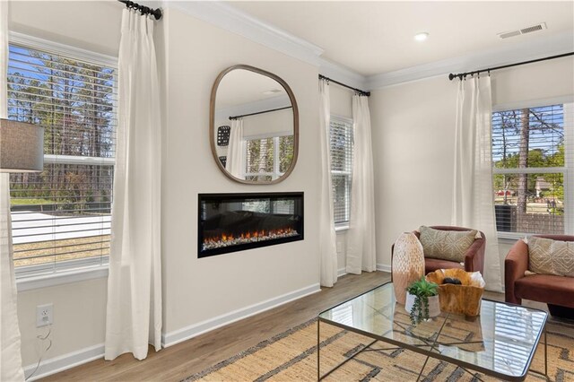 living area with hardwood / wood-style floors, plenty of natural light, and ornamental molding