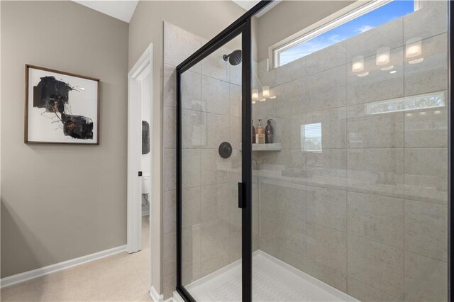 bathroom featuring a shower with door and toilet