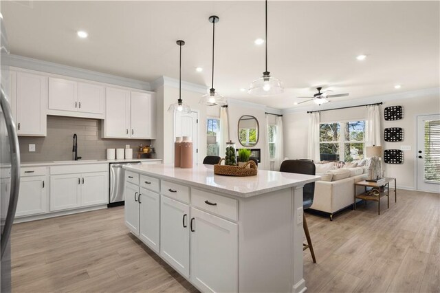 kitchen featuring dishwasher, hanging light fixtures, sink, and white cabinets