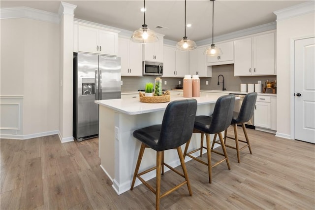 kitchen with light wood-type flooring, appliances with stainless steel finishes, an island with sink, and white cabinets