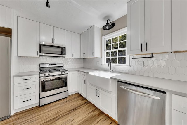 kitchen featuring light hardwood / wood-style floors, white cabinetry, sink, and appliances with stainless steel finishes