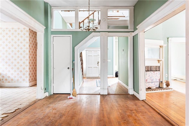 entrance foyer featuring hardwood / wood-style flooring, ornate columns, and a notable chandelier