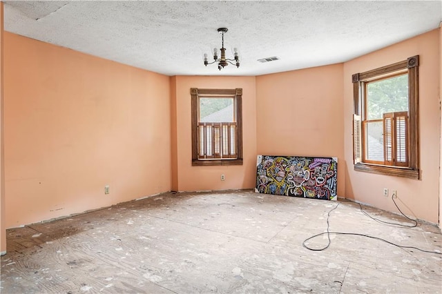 unfurnished room featuring a chandelier and a textured ceiling