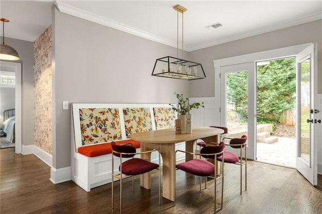 dining room featuring ornamental molding, baseboards, visible vents, and wood finished floors