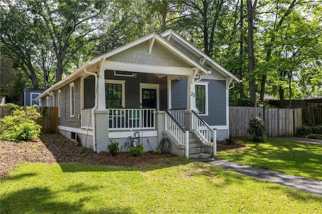 bungalow with covered porch, fence, and a front yard