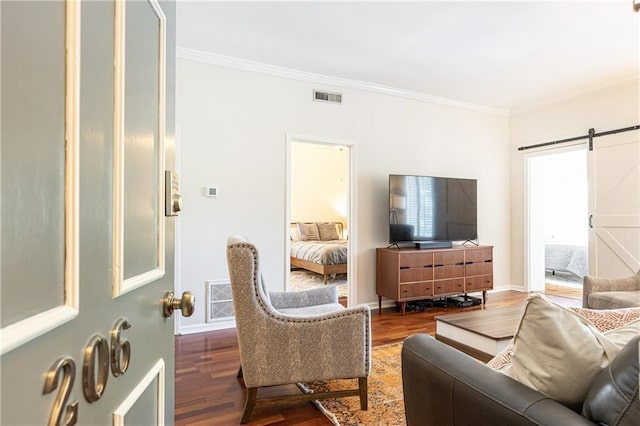 living room featuring hardwood / wood-style floors, a barn door, and ornamental molding