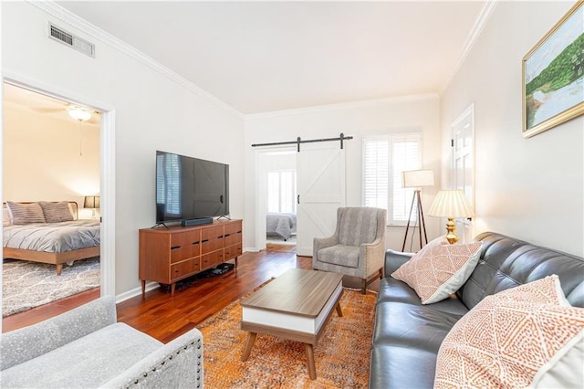 living room featuring hardwood / wood-style floors, a barn door, and crown molding