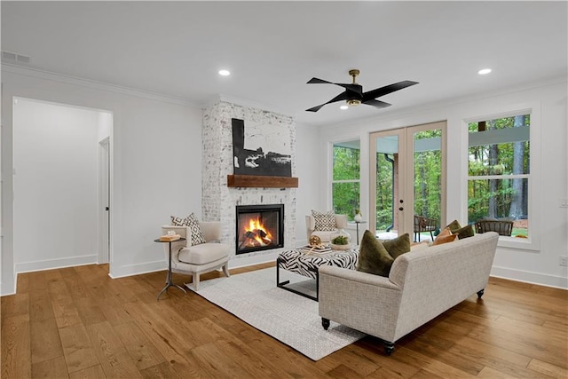 living room with a wealth of natural light, a stone fireplace, and light wood-type flooring