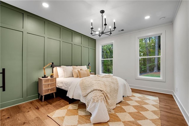 bedroom featuring light wood-type flooring, crown molding, and a notable chandelier