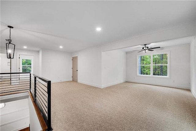 carpeted empty room featuring a wealth of natural light, ceiling fan, and crown molding