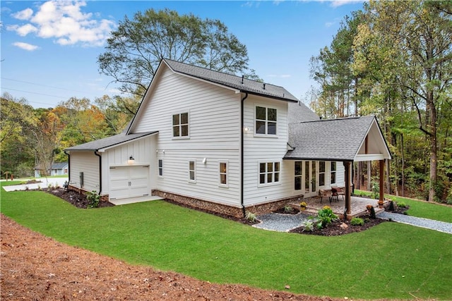 rear view of property with a patio, a garage, and a yard