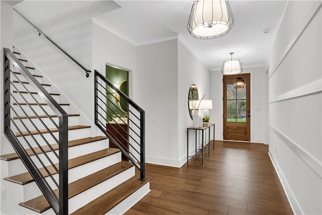 entrance foyer featuring dark wood-type flooring, crown molding, and an inviting chandelier