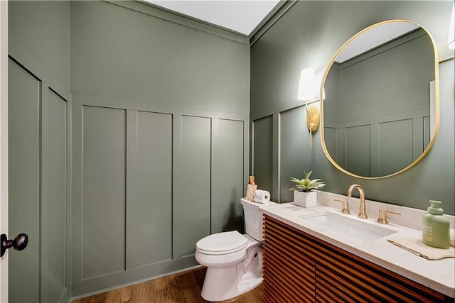 bathroom featuring toilet, vanity, wood-type flooring, and crown molding