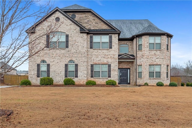 view of front of home with brick siding, a front lawn, and fence