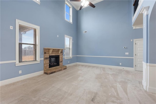 unfurnished living room with a stone fireplace, baseboards, and light carpet