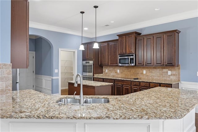 kitchen featuring a sink, light stone countertops, wainscoting, and stainless steel appliances