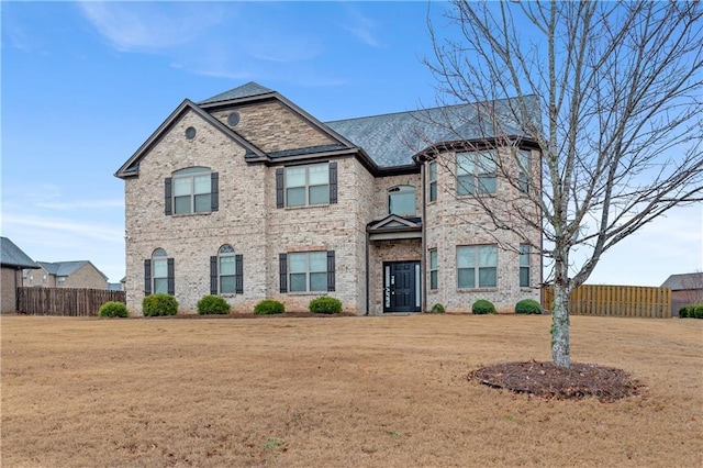 view of front of property featuring brick siding, a front yard, and fence