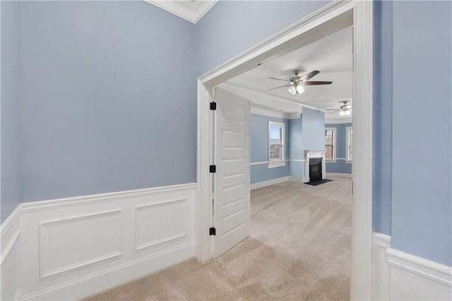 hall featuring light carpet, wainscoting, and ornamental molding