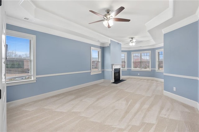 empty room featuring visible vents, a fireplace with flush hearth, crown molding, light carpet, and a raised ceiling