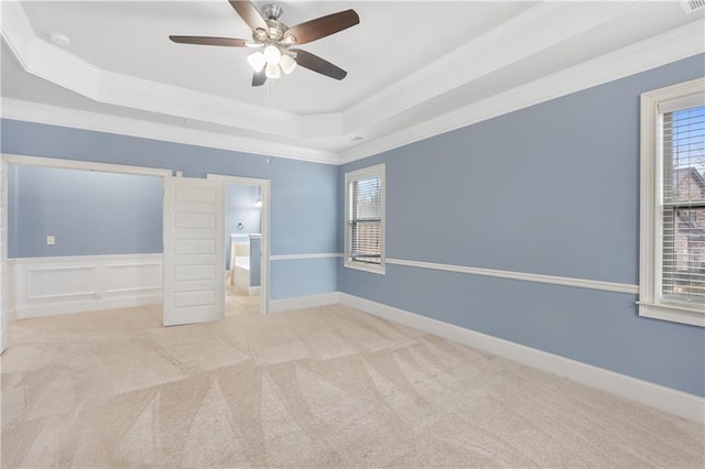 unfurnished bedroom featuring a tray ceiling, multiple windows, carpet, and ornamental molding