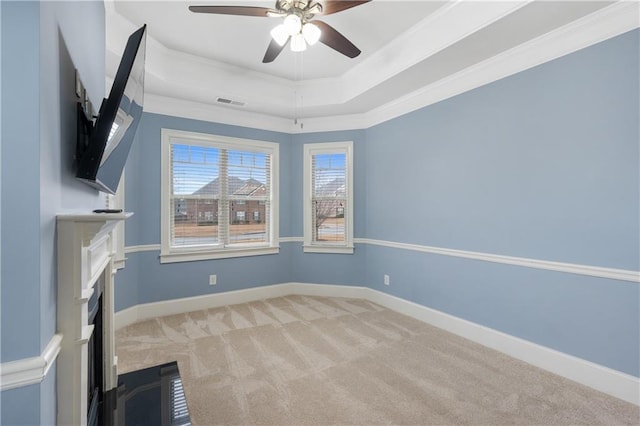 interior space featuring a tray ceiling, crown molding, baseboards, and carpet floors