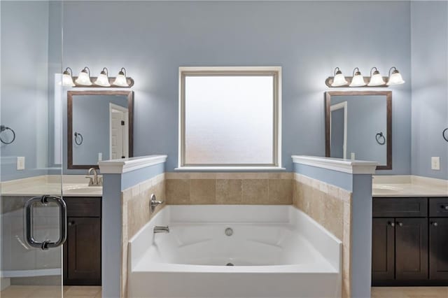 bathroom with a garden tub, two vanities, and a sink