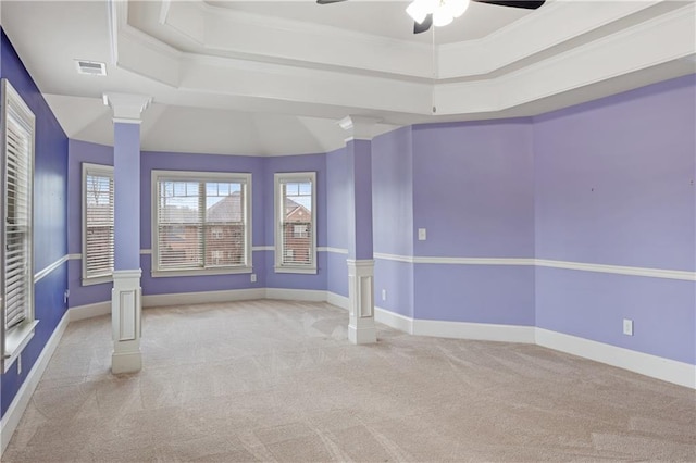 unfurnished room with baseboards, a raised ceiling, ornate columns, and carpet floors