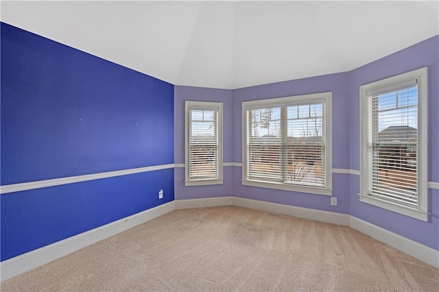 spare room featuring baseboards, carpet floors, and vaulted ceiling