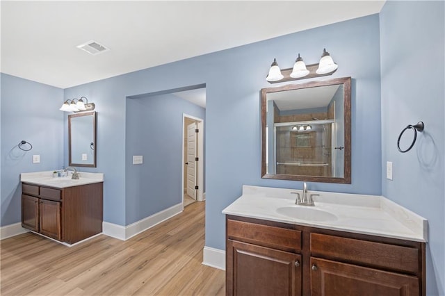 bathroom featuring a shower stall, wood finished floors, baseboards, and a sink