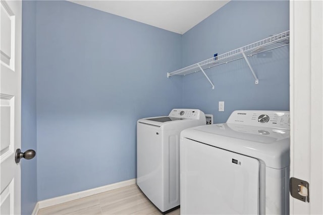 laundry room with light wood-style flooring, baseboards, washing machine and dryer, and laundry area