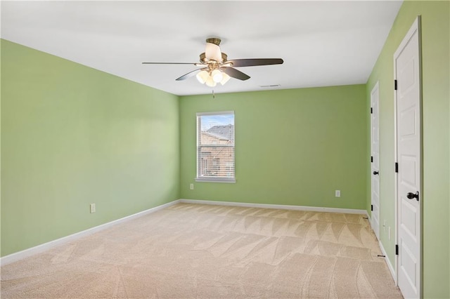 carpeted empty room featuring visible vents, a ceiling fan, and baseboards