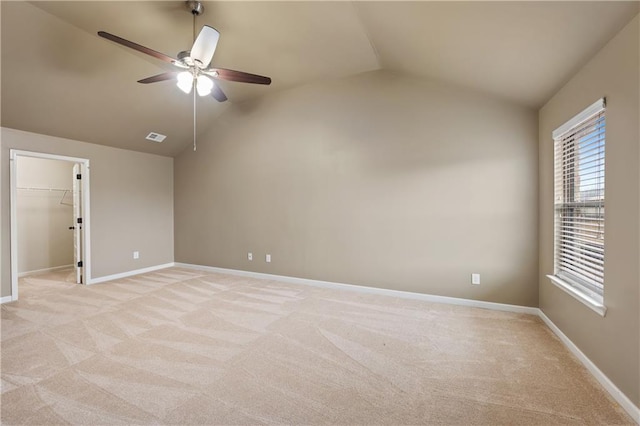 unfurnished room with vaulted ceiling, light colored carpet, visible vents, and baseboards