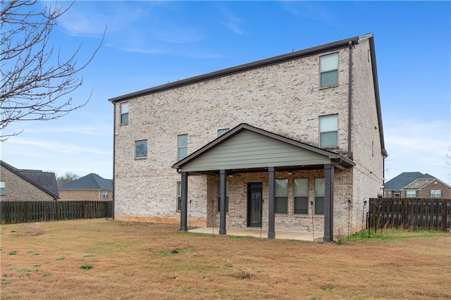 rear view of property featuring a patio, a ceiling fan, a fenced backyard, a lawn, and brick siding