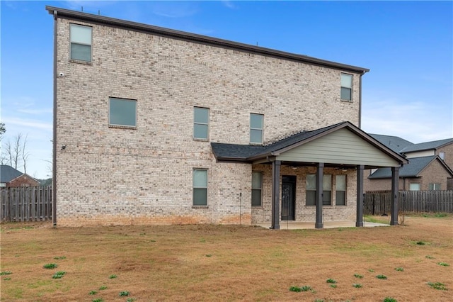 back of house featuring a lawn, a fenced backyard, brick siding, and a patio area