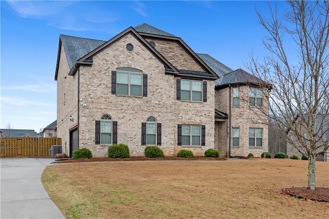 view of front of house with cooling unit, brick siding, a front yard, and fence