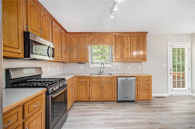 kitchen featuring a sink, light countertops, stainless steel appliances, and brown cabinets