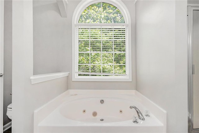 full bath featuring a whirlpool tub and toilet