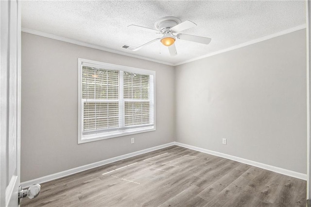 spare room with visible vents, a ceiling fan, wood finished floors, and ornamental molding