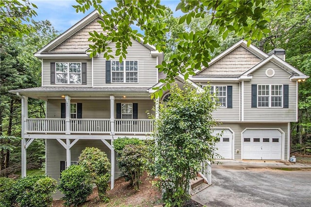 view of front of property featuring covered porch, a garage, a chimney, and aphalt driveway
