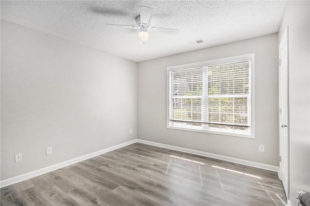 spare room featuring a textured ceiling, baseboards, a ceiling fan, and wood finished floors