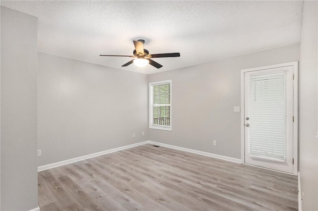 spare room with a textured ceiling, baseboards, a ceiling fan, and wood finished floors