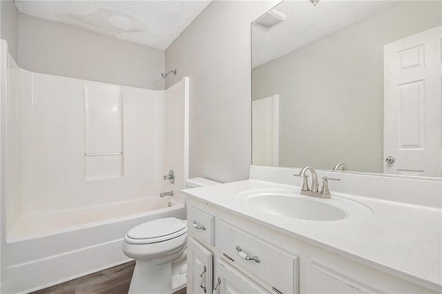 full bath with a textured ceiling, wood finished floors, vanity, toilet, and shower / bathtub combination