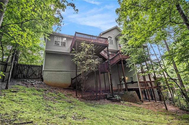 back of property with stairs, a lawn, fence, and a deck