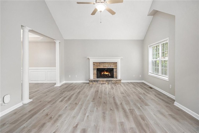 unfurnished living room with ceiling fan, a fireplace, light wood-style floors, high vaulted ceiling, and ornate columns