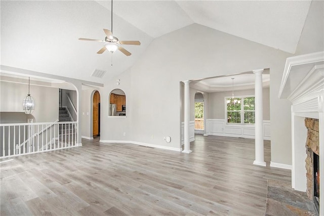 unfurnished living room featuring visible vents, a fireplace, wood finished floors, high vaulted ceiling, and ceiling fan with notable chandelier