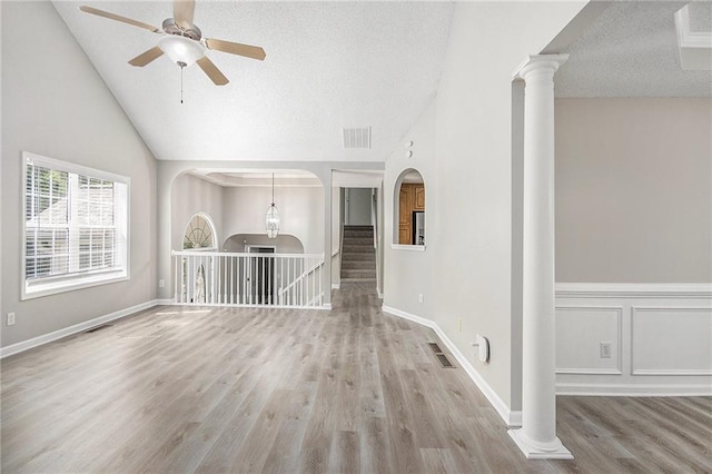 empty room featuring visible vents, wood finished floors, ornate columns, a textured ceiling, and a ceiling fan