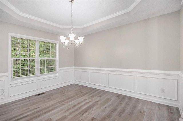 unfurnished dining area with a chandelier, a tray ceiling, visible vents, and ornamental molding